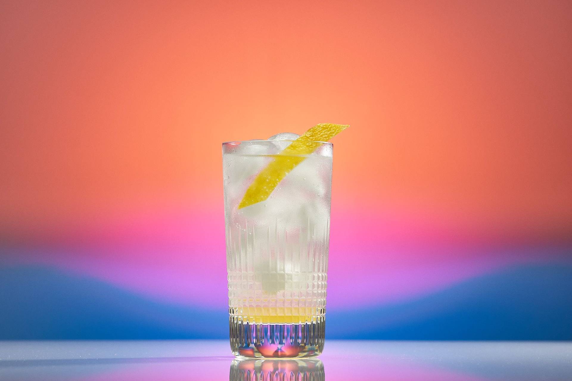 spicy-ginger-lemon-mocktails a glass of spicy ginger lemon mocktail on rainbow colored background