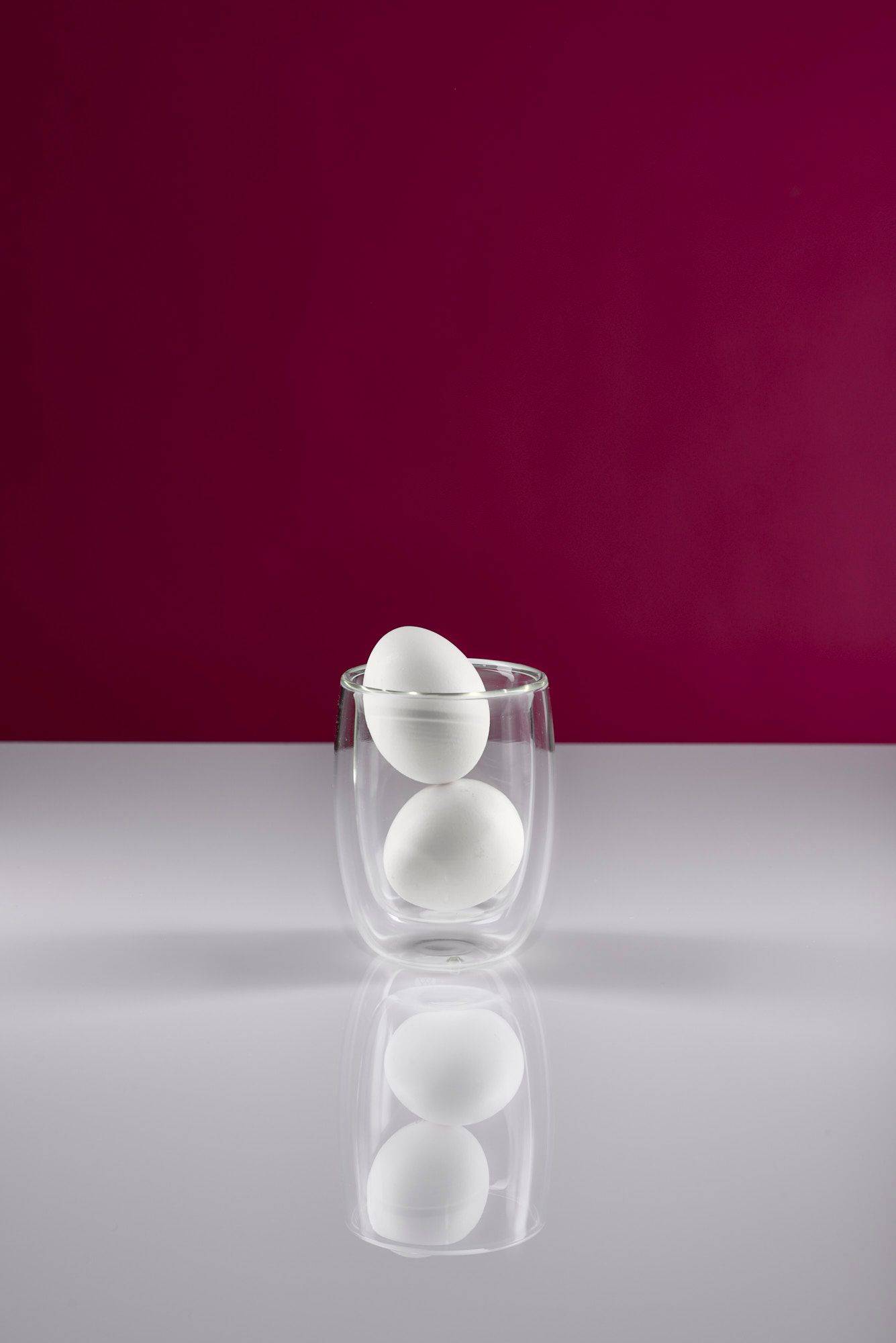 eggs two white eggs in a glass with white and pink background