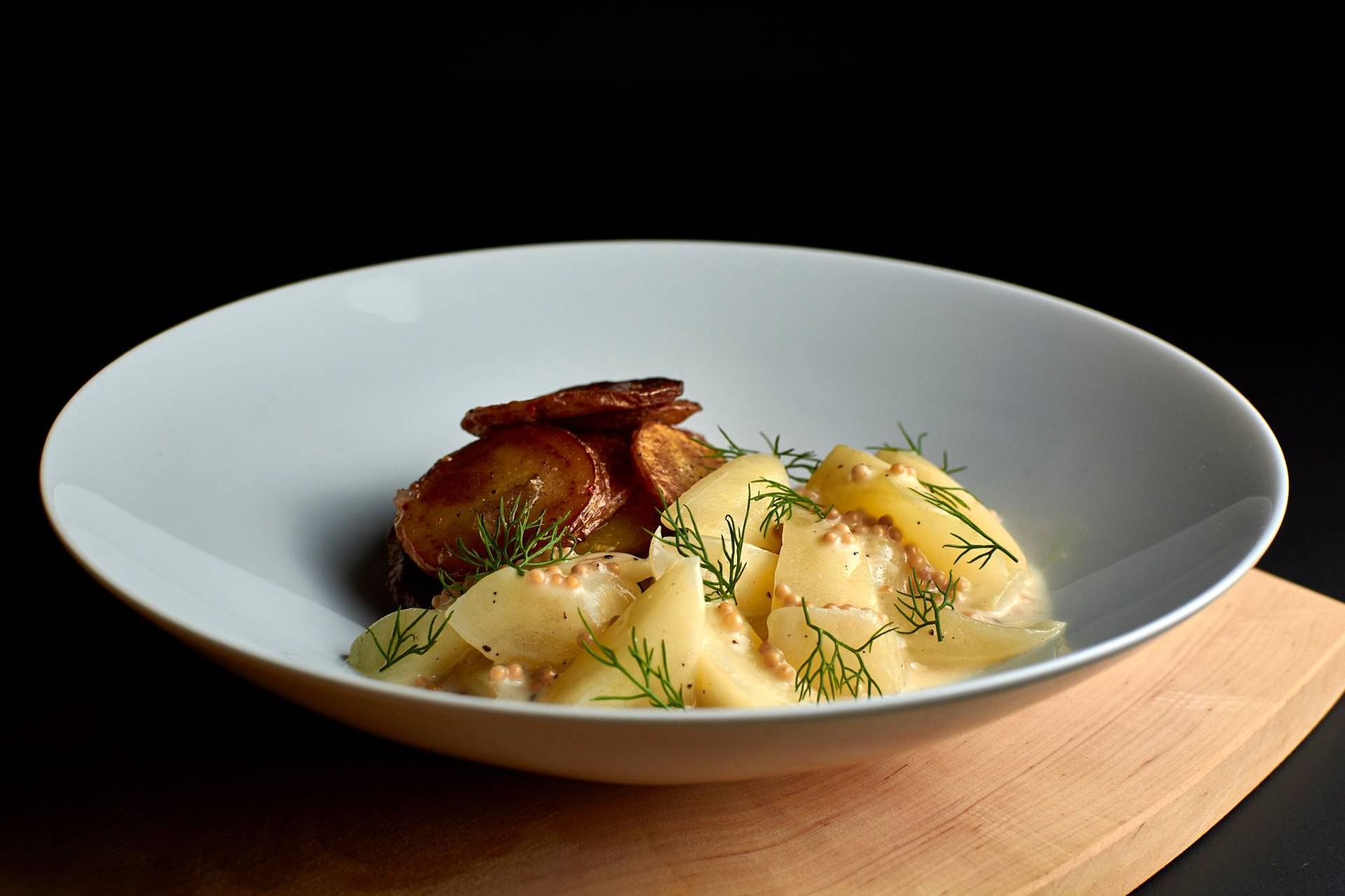 braised-cucumbers-with-roasted-potatoes braised cucumbers with roasted potatoes in a white bowl on black background