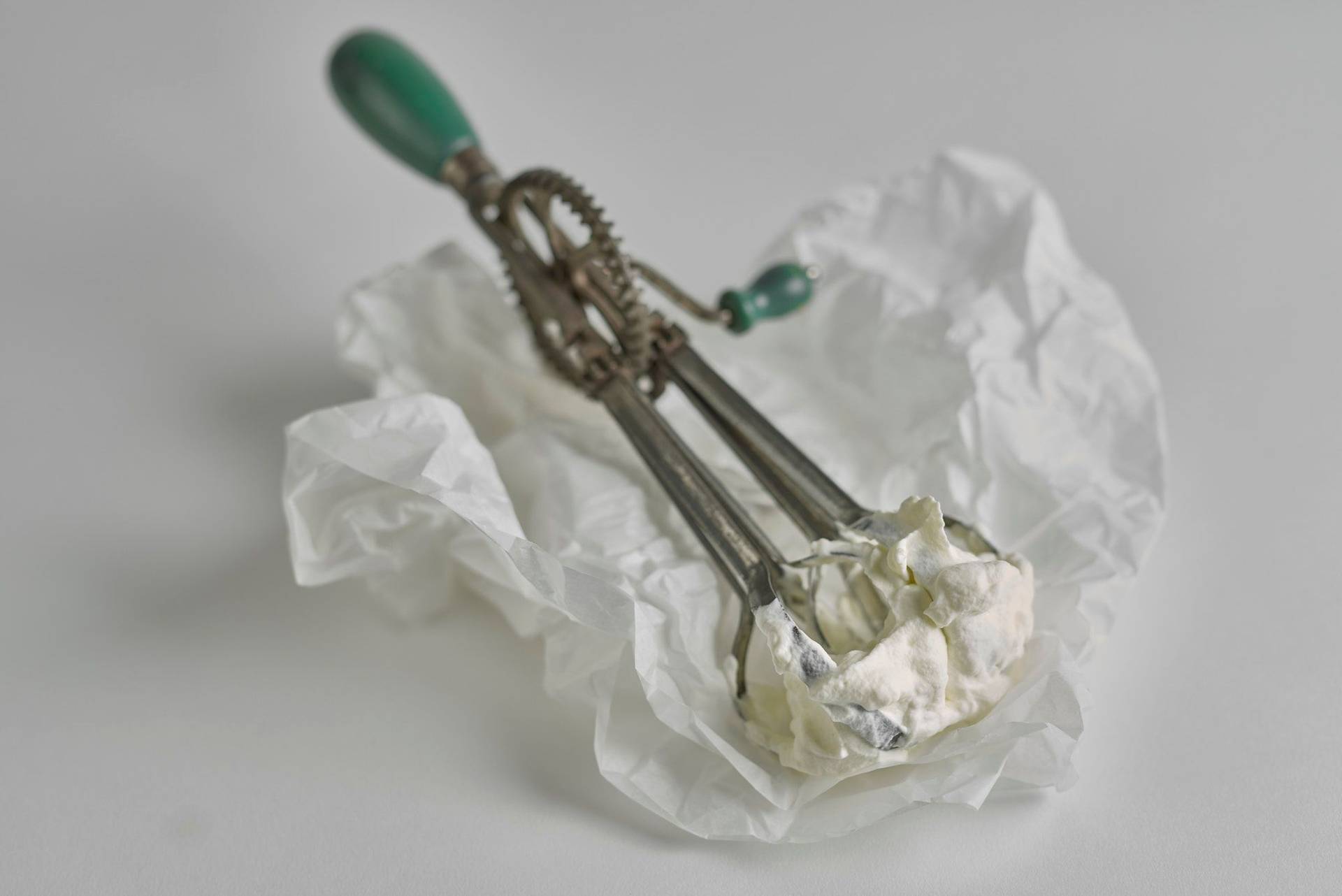 whipped-cream whipped cream on a vintage hand mixer with white background