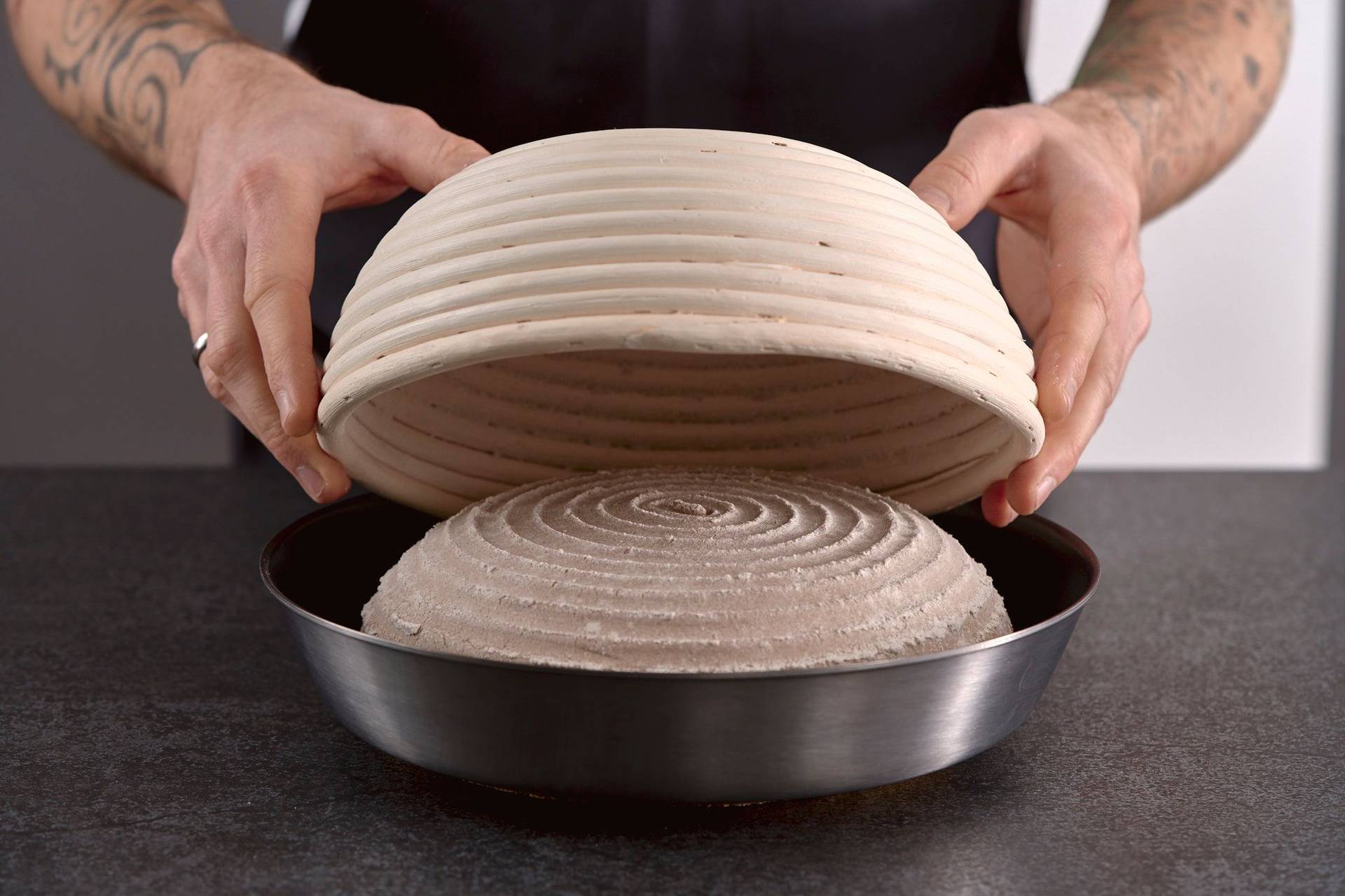 turning-over-proofed-rye-sourdough-bread man turning over proofed rye sourdough bread into a pan in home kitchen