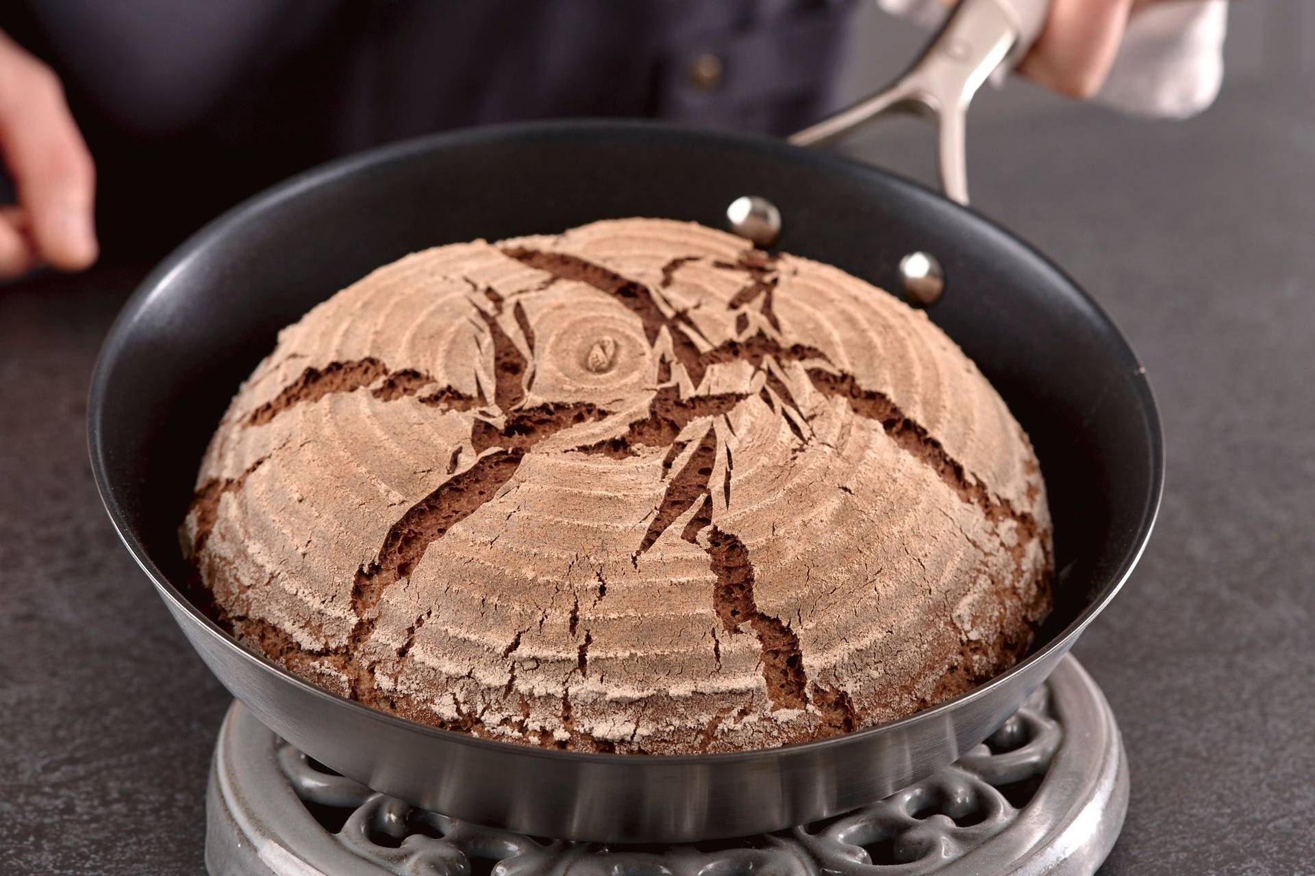 pan-baked-rye-sourdough-bread man holds a pan baked rye sourdough bread in home kitchen
